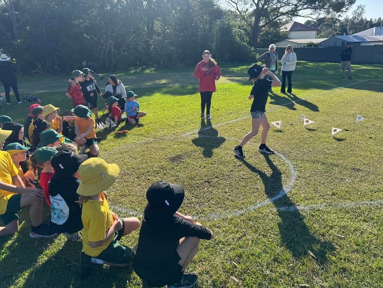 student throwing shot put with spectators.